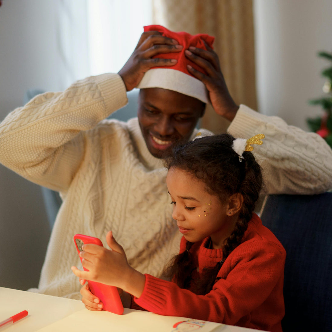 dad and daughter listening to Christmas songs on a phone
