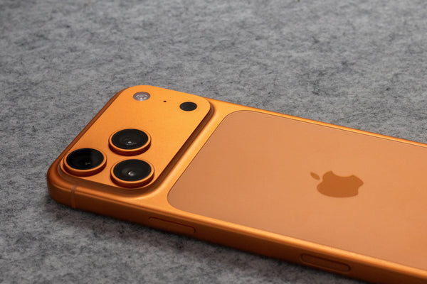 Apple iPhone 17 in orange lying on the ground, comparison to iPhone 16 series