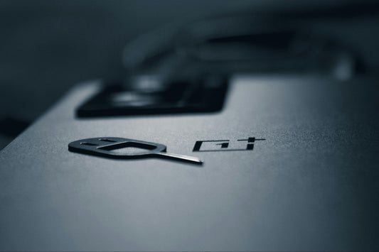 Close-up of a OnePlus with a SIM needle on a dark background