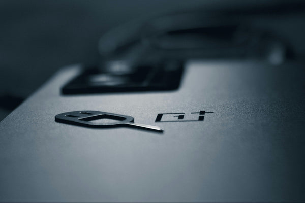Close-up of a OnePlus with a SIM needle on a dark background