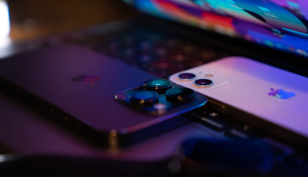 Two Apple smartphone camera on a laptop keyboard with a blurred background
