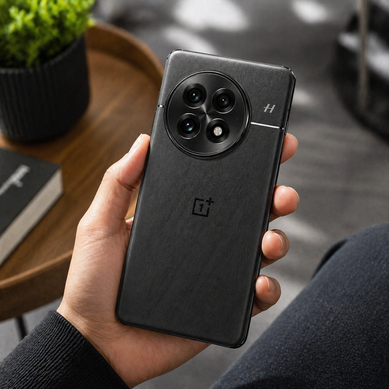 Person holding a black OnePlus smartphone with a blurred indoor background